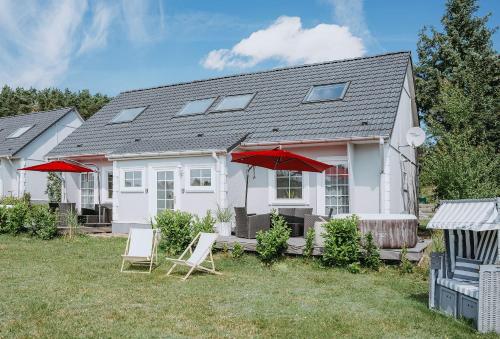 a white house with red umbrellas in the yard at Ferienhäuser Insel Usedom Haus Jojo 7 - Blick aufs Achterwasser! Whirlpool und Sauna in Lütow