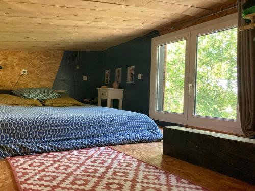 une chambre avec un lit et une grande fenêtre dans l'établissement UpCycling Cabane, à Millau
