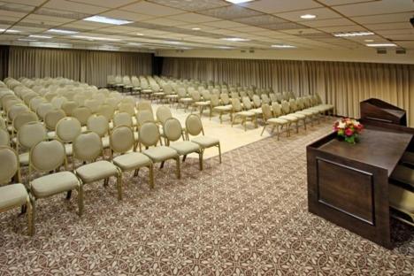 a conference room with a stage and chairs and a podium at Royal Plaza Hotel in Tiberias