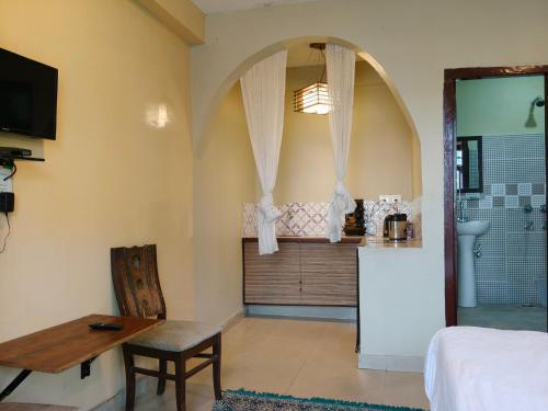 a room with a bed and a table and a kitchen at Himalayan horizon and cafe in Dharamshala