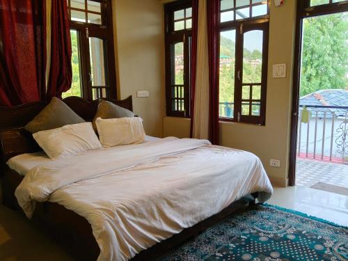 a bedroom with a large bed with windows at Himalayan horizon and cafe in Dharamshala