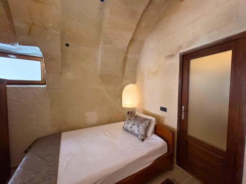 a small room with a bed with a lamp and a door at Elysee Cave House in Goreme