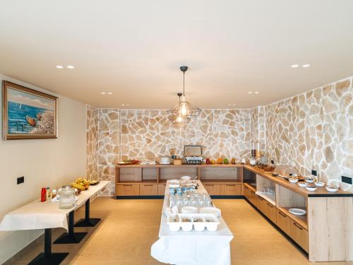 a kitchen with wooden cabinets and a stone wall at Sunset Shoreline Saranda - Sea View - Free Private Parking - Pool in Sarandë
