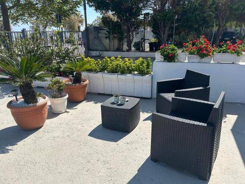a patio with chairs and potted plants and flowers at SoleeMare Barletta in Barletta