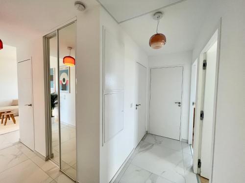 un couloir avec des murs blancs et un miroir dans l'établissement PGH n42-Roof-Top avec Terrasse et Parking Prive, à La Grande Motte