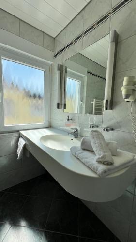 a white bathroom with a sink and a mirror at Gästehaus Kliebenstein in Saarwellingen