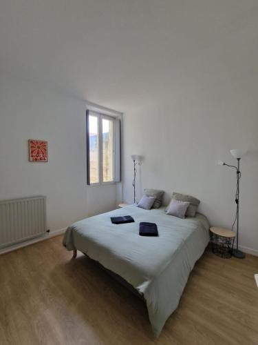 une chambre avec un grand lit dans une pièce blanche dans l'établissement Le Moulin hyper centre Libourne, à Libourne