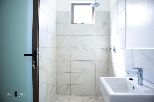 a white bathroom with a sink and a shower at Lihanda Villa in Kilifi