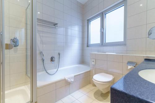 a bathroom with a shower and a toilet and a sink at Stadthotel Pfeffermühle in Gengenbach