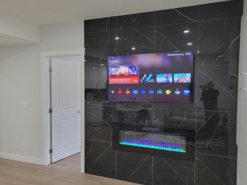 a flat screen tv on a wall in a room at Cozy and Modern Suite - Your Home Away from Home! in Calgary