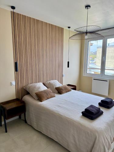 une chambre avec un grand lit avec deux serviettes dessus dans l'établissement Appartement neuf contemporain, à Lourdes