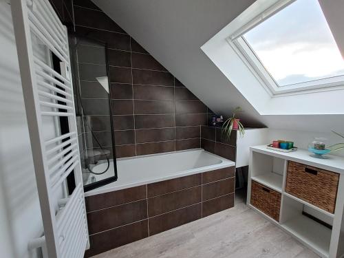 a bathroom with a bath tub and a skylight at Chambre 5 mn de la gare - Tres beau jardin in Le Mans