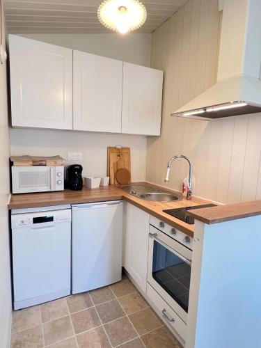 une cuisine avec des armoires blanches et un évier dans l'établissement 138 - Roses des Sables Ocean View Full Village Center, à Saint-Martin-de-Ré