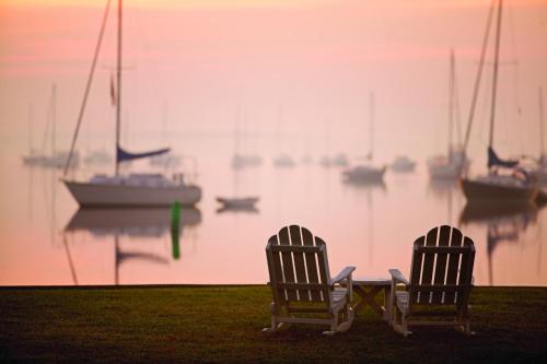 two chairs sitting next to a table with boats in the water at Inn at Perry Cabin in Saint Michaels