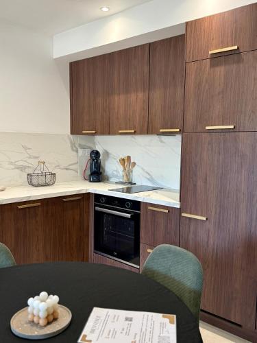 - une cuisine avec des placards en bois, une cuisinière et une table dans l'établissement Appartement neuf contemporain, à Lourdes