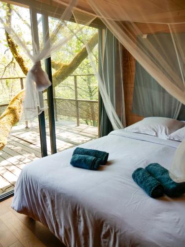 une chambre avec un lit avec deux serviettes bleues dessus dans l'établissement Cabane perchée - lac privé, spa & nature, à Sadirac