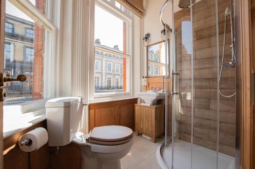 a bathroom with a toilet and a shower and a window at The Old Farmhouse Pub and Rooms in London