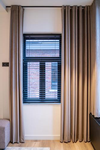 a living room with a window with curtains and a couch at Boutique Hotel Annamaes, Maastricht-Hoge Kempen in Lanaken