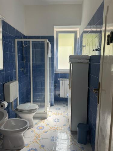a blue tiled bathroom with two toilets and a shower at Appartamento in villa in Forio d'Ischia