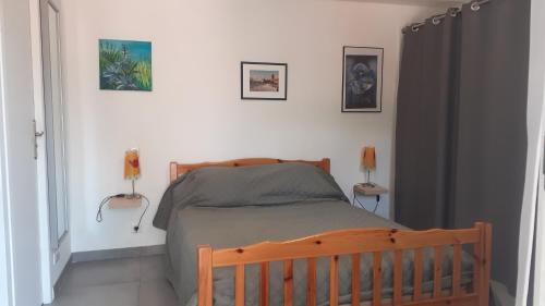 - une chambre avec un lit en bois et trois photos sur le mur dans l'établissement LA CIGALE STUDIO à port vendres, à Port-Vendres