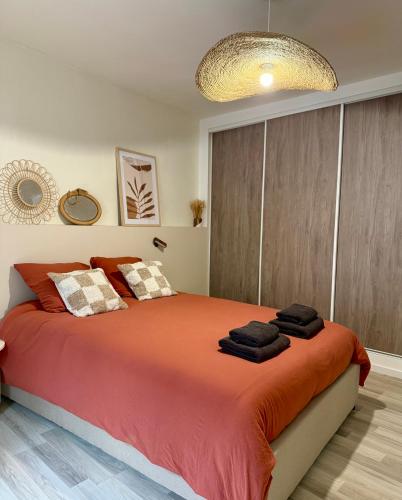 - une chambre avec un grand lit et une grande couverture orange dans l'établissement Le cocon coloré - Appartement centre ville, à Lourdes