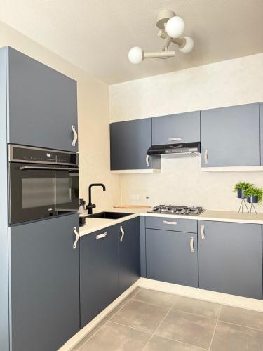 a kitchen with blue cabinets and a ceiling fan at Appartement Duinhof, Cadzand-Bad in Cadzand-Bad