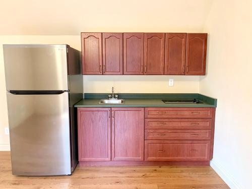 a kitchen with a stainless steel refrigerator and wooden cabinets at Private Bright Coach House - Near Pearson Airport & Downtown Toronto in Brampton