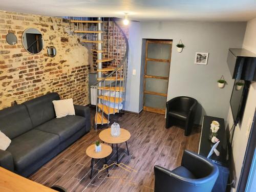 a living room with a couch and tables and a brick wall at Maison cosy avec jardin privé proche gare in Le Mans