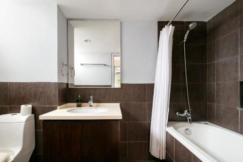 ein Badezimmer mit Waschbecken, Badewanne und Spiegel in der Unterkunft 3-Bedroom Stay at Macalister Road & Georgetown, Noble Villa Penang in George Town