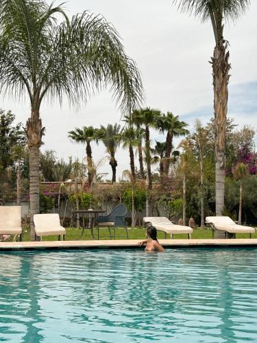 a person in a swimming pool with palm trees at FEKHARA Country Club in Marrakech