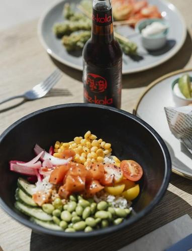 a bowl of food with vegetables and a bottle of beer at MYND Adeje in Adeje