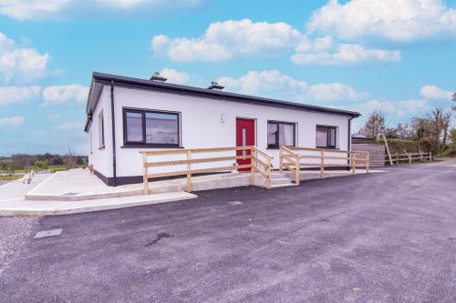 a small white building with a red door on a street at Eden House and Pet Farm in Feevaghmore