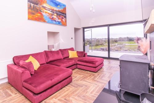 a living room with a red couch and a large window at Eden House and Pet Farm in Feevaghmore