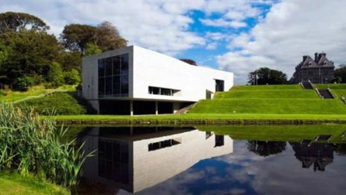 a white building with its reflection in the water at Eden House and Pet Farm in Feevaghmore
