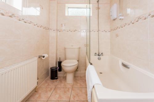 a bathroom with a toilet and a tub and a sink at Prebends Field in Gilesgate