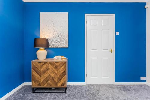 a blue room with a white door and a table with a lamp at Prebends Field in Gilesgate