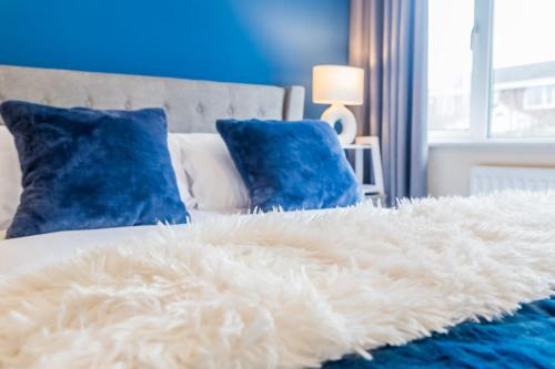 a white furry blanket on a bed with blue pillows at Prebends Field in Gilesgate