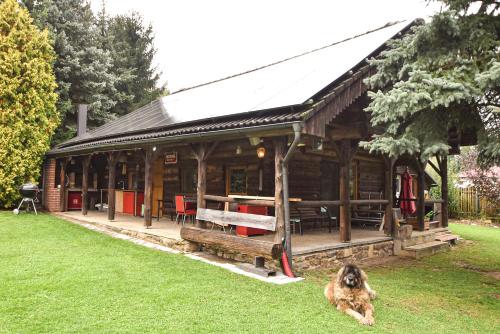 a wooden cabin with a dog sitting in the grass at Wooden house in Vysočina in Jihlava
