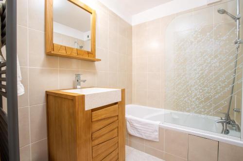 une salle de bain avec un lavabo, une baignoire et un miroir dans l'établissement Hidden 2 bed gem in prime central location, à Morzine