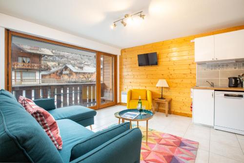 un salon avec un canapé bleu et une cuisine dans l'établissement Hidden 2 bed gem in prime central location, à Morzine