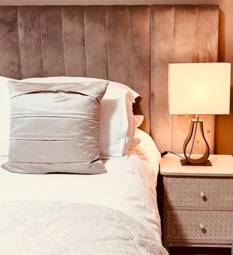 a bed with white sheets and a lamp on a nightstand at Moffat House in Moffat