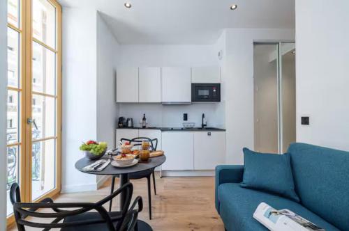 un salon avec un canapé bleu et une table dans l'établissement Cozy studio near the sea, à Nice