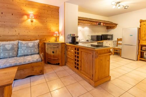 a kitchen with wooden walls and a counter with a refrigerator at Alba Lodge, 2 min de la télécabine, vue montagnes in Brides-les-Bains