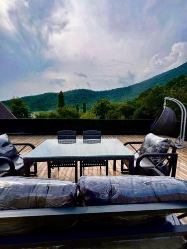 a table and chairs on a deck with a view at Qafqaz Mountain Terrace İndoor Hot Pool in Gabala