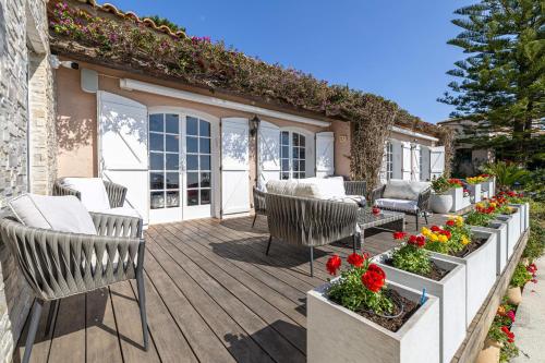 una terraza de madera con sillas y flores. en REF 2165- Mandelieu La Napoule- Sea view Villa for rent, en Mandelieu-la-Napoule