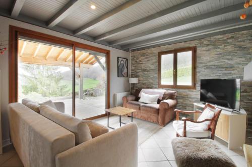 un salon avec un canapé et une télévision dans l'établissement Le petit belvédère chalet avec piscine & vue lac, à Ontex
