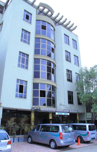 two cars parked in front of a building at Hotel Lobelia in Addis Ababa