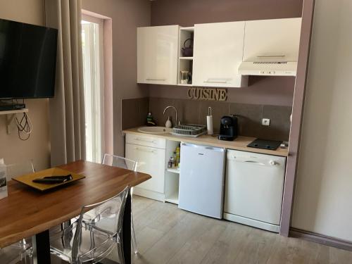 une cuisine avec des placards blancs, une table et un comptoir dans l'établissement Le Chalet de Malo, à Biscarrosse