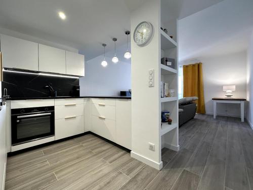 une cuisine avec des placards blancs et une horloge murale dans l'établissement Magnifique appartement 3 pièces avec double vue mer, à Ajaccio