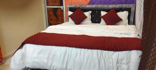 un letto con lenzuola e cuscini rossi e bianchi di Hotel O Suryavanshi Palace a Ayodhya